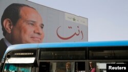 FILE - People ride on a bus as posters with Egypt's President Abdel Fattah al-Sissi are displayed in Cairo, Egypt. 