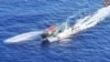 FILE - In this frame grab from aerial video footage taken on March 5, 2024, and released by the Philippine Coast Guard (PCG), a Chinese Coast Guard ship (R) deploys a water cannon at the Philippine military-chartered civilian boat Unaizah.