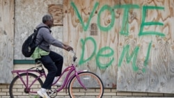 FILE - A man rides his bike past a boarded-up business, May 28, 2020, in East Cleveland, Ohio. As of the end of May, about 1.3 million Ohioans had filed unemployment claims in the past 10 weeks, the state said.