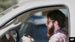 FILE - An man works his phone as he drives through traffic in Dallas, Tuesday, Feb. 26, 2013. Texas lawmakers are considering a statewide ban on texting while driving. (AP Photo/LM Otero)