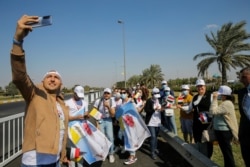 A man takes selfies as he waits for the arrival of Pope Francis, at Baghdad Airport Road, in Baghdad, Iraq March 5, 2021.