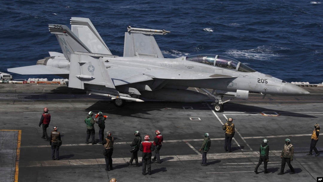 Un F-18 Super Hornet de la Marina de EEUU y miembros de la tripulación se ven en la cubierta de vuelo del USS Nimitz frente a la costa de Busan, Corea del Sur, el lunes 27 de marzo de 2023.