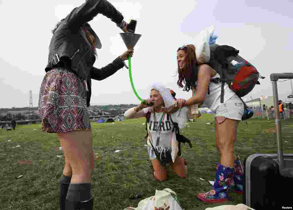 Bride-to-be Lizzie Chapman drinks cider through a funnel on arriving at Glastonbury, where she celebrates her hen night, on the second day of Glastonbury music festival at Worthy Farm in Somerset, Britain.