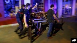 FILE - In this Nov. 14, 2015, photo, a person is being evacuated after a shooting, outside the Bataclan theater in Paris. 