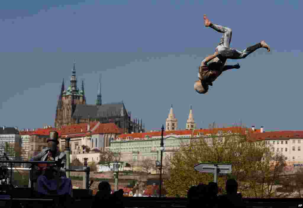  A member of the artistic group Cirk La Putyka performs on a trampoline while another group member plays guitar and sings to entertain residents as movement remains restricted to stem the spread of the coronavirus, in Prague, Czech Republic.