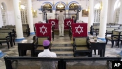 FILE - Moses Samuels sits alone at the synagogue in Rangoon, as his son Sammy Samuels reads from a prayer book, May 2, 2001. 