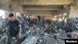 Palestinians inspect the site of an Israeli strike on a school sheltering displaced people, amid the Israel-Hamas conflict, in Nuseirat in the central Gaza Strip, Oct. 24, 2024.