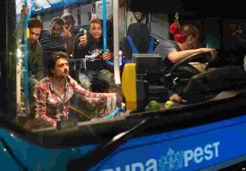 Migrants flash victory sign and thumb-up after arriving at the border station between Hegyeshalom, Hungary, and Nickelsdorf, Austria, Saturday morning Sept. 5, 2015.