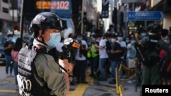 Un policía antidisturbios sostiene un lanzador de gas pimienta frente a los manifestantes el domingo 28 de junio, cuando el gobierno está a punto de aprobar la Ley de Seguridad Nacional.