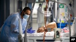 A medical staff member speaks with a COVID-19 patient in the infectious disease ward of the Strasbourg University Hospital, eastern France, Jan. 13, 2022.