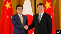 资料照：中国国家主席习近平和大阪与日本首相安倍晋三握手。（2019年6月27日）