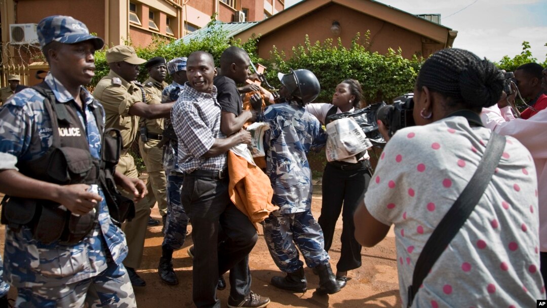 FILE - Reporters and members of Uganda's Human Rights Network for Journalists struggle with police during a protest in downtown Kampala, Uganda, May 28, 2013.