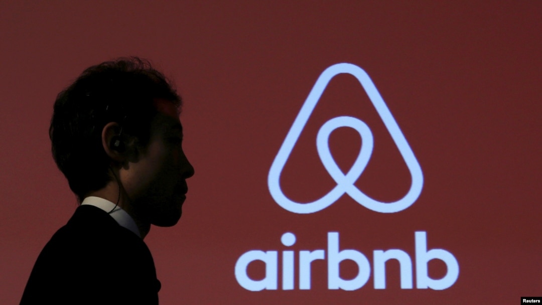 Seorang pria melewati logo Airbnb, situs penyewaan penginapan (foto: ilustrasi). 