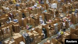 Workers collect customer orders during Black Friday deals week at an Amazon fulfilment centre in Hemel Hempstead, Britain November 25, 2015. 