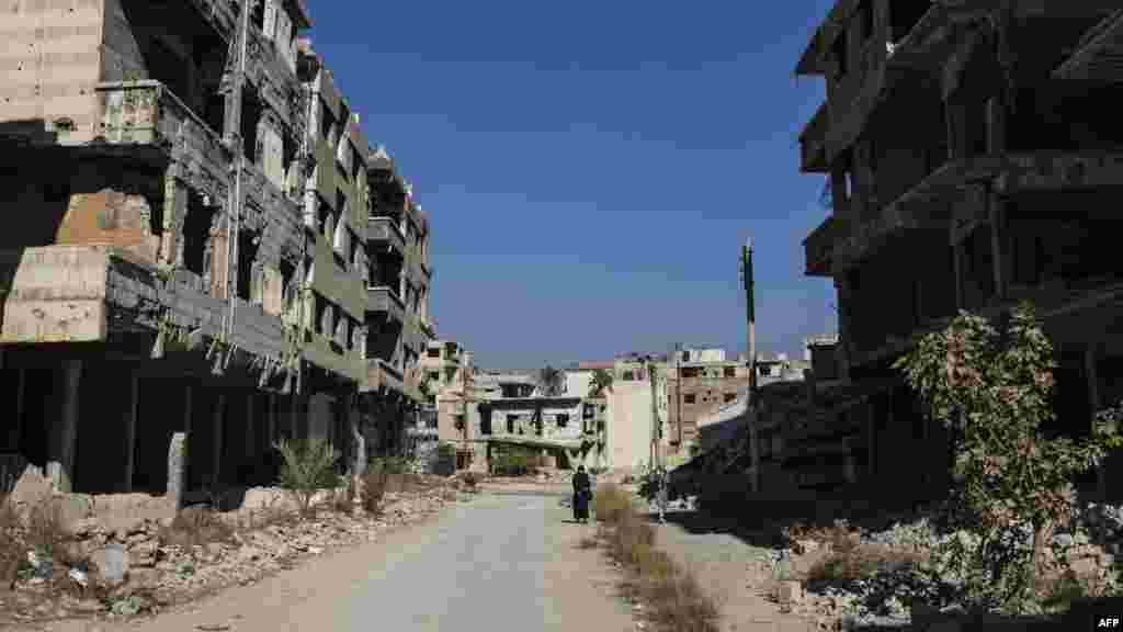 Dua wanita berjalan melewati bangunan-bangunan yang hancur di kota Harasta di Ghouta Timur di pinggiran Damaskus, Suriah. (AFP)&nbsp;