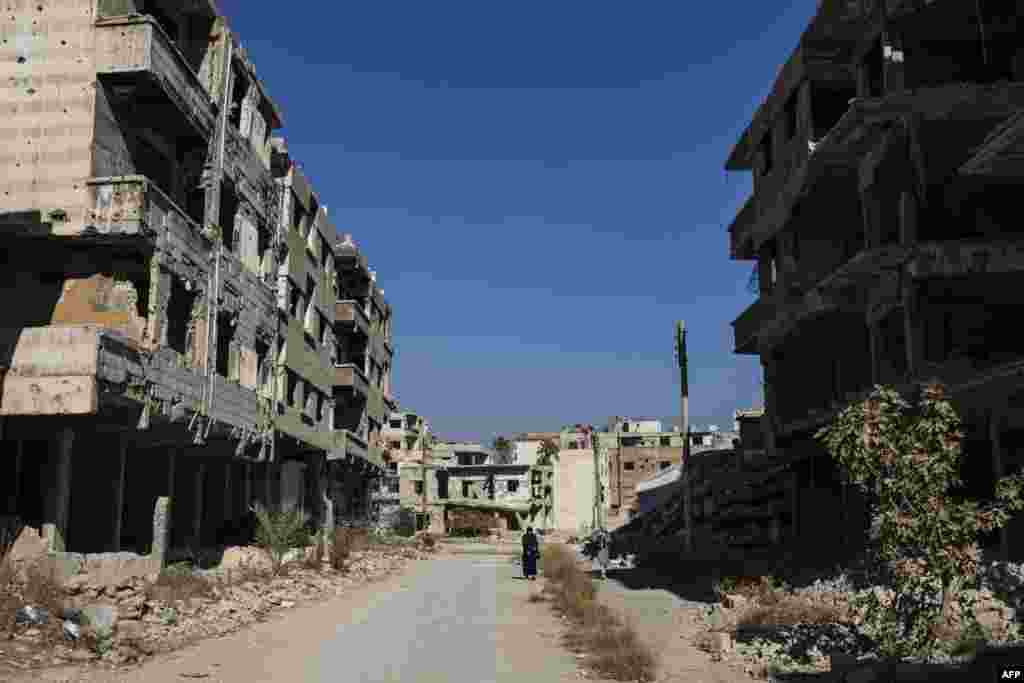 Women walk past destroyed buildings in the city of Harasta in Eastern Ghouta on the outskirts of Damascus, Syria.