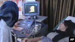 Dr. Mutahar Fauzia (L) uses an ultrasound machine to check on the development of Laiqa Ahmed's unborn child