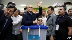 이란 대통령 보궐선거의 개혁파 후보인 마수드 페제시키안 후보가 28일 투표한 후 손을 들어보이고 있다. 