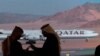 FILE - Journalists chat as video of a plane carrying Qatar's emir, Sheikh Tamim bin Hamad al-Thani, is shown on a screen while landing at al-Ula airport, where the 41st Gulf Cooperation Council meeting takes place, in Saudi Arabia, Jan. 5, 2021.