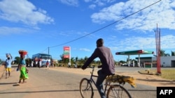 FILE - A man bikes past a gas station, June 11, 2018, in Macomia, Northern Mozambique. Cabo Delgado, a northern province expected to become the center of a natural gas industry, has seen a string of assaults on security forces and civilians since October.