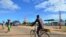 FILE - A man cycles along a street past a gas station in Macomia, Cabo Delgado province, Northern Mozambique, June 11, 2018.