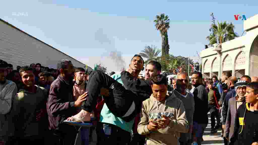 Un hombre es llevado en brazos mientras los prisioneros palestinos liberados son recibidos, tras ser entregados por Israel como parte de un intercambio de rehenes por prisioneros.