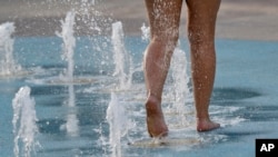 Taylor Jeremiah cools off while walking through a fountain early in downtown Phoenix, July 23, 2018.