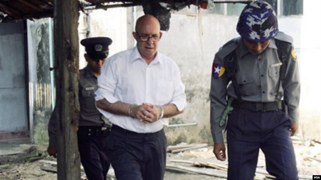 Petugas keamanan Burma mengawal Ross Dunkley keluar dari pengadilan di kota Kamayut, Kamis (3/3).