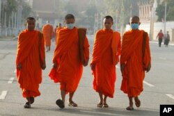 Buddhist monks wear masks as they walk near Royal Palace in Phnom Penh, Cambodia, Jan. 28, 2020.