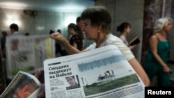 An employee distributes newspapers, with a photograph (L) of former U.S. spy agency contractor Edward Snowden seen on a page, at an underground walkway in central Moscow, July 2, 2013. 