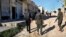 Members of the Kurdish internal security forces pass damaged shops in the area where an explosion hit U.S.-led coalition vehicles, killing an American soldier and a British soldier, in Manbij, Syria, March 31, 2018.