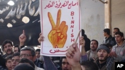 Anti-Syrian regime protester holds up Arabic placard reading: "the victory fingers over the [presidential] palace," during a demonstration, at Binnish village, in Idlib province, Syria.