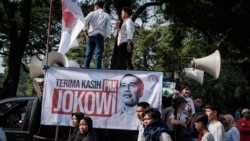 Massa pendukung pemerintah membentangkan poster bertuliskan ucapan terima kasih kepada Presiden Joko Widodo, dua hari menjelang pelantikan Presiden terpilih Prabowo Subianto, Jumat, 18 Oktober 2024. (Foto: Yasuyoshi Chiba/AFP)