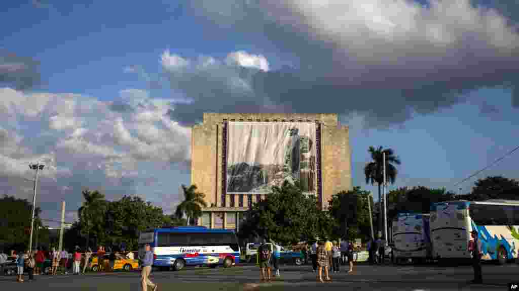 Les touristes devant la Place de la Révolution alors que les travailleurs accrochent une bannière du défunt Fidel Castro, le 27 novembre 2016.