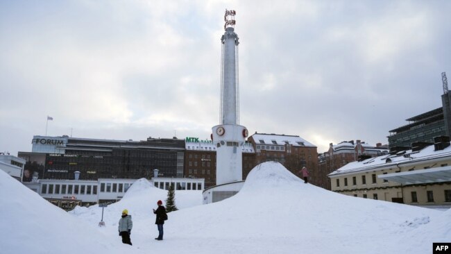 People stand in an area covered with snow in the Finnish capital of Helsinki on Jan. 3, 2024, as a cold snap hit the country. Despite the frigid temperatures across much of Europe, analysts say Europe is less dependent on Russian energy imports this winter.