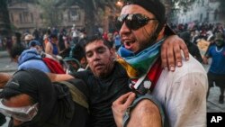 An injured anti-government demonstrator is carried to safety during clashes with the Chilean police in Santiago, Chile, Nov. 12, 2019.