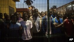 African migrants watch as others arrive at a temporary holding center after scaling a metallic fence that divides Morocco and the Spanish enclave of Melilla, May 28, 2014.