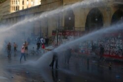 Riot police use water cannons against anti-government protesters during a protest marking the first anniversary of the massive blast at Beirut's port, near Parliament Square, In Beirut, Lebanon, Aug. 4, 2021.