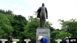 Workers arrange flower pots in front of a monument of Soviet founder Vladimir Lenin in Hanoi on June 18, 2024.