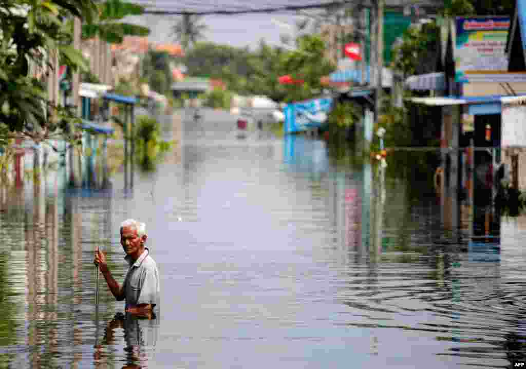 October 21: A man wades through the isolated and flooded village of Kajee Nush in Pathum Thani province, near Bangkok. REUTERS/Damir Sagolj