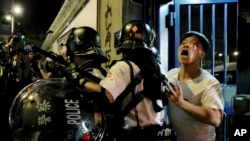 A bleeding man is taken away by policemen after attacked by protesters outside Kwai Chung police station in Hong Kong, Wednesday, July 31, 2019.