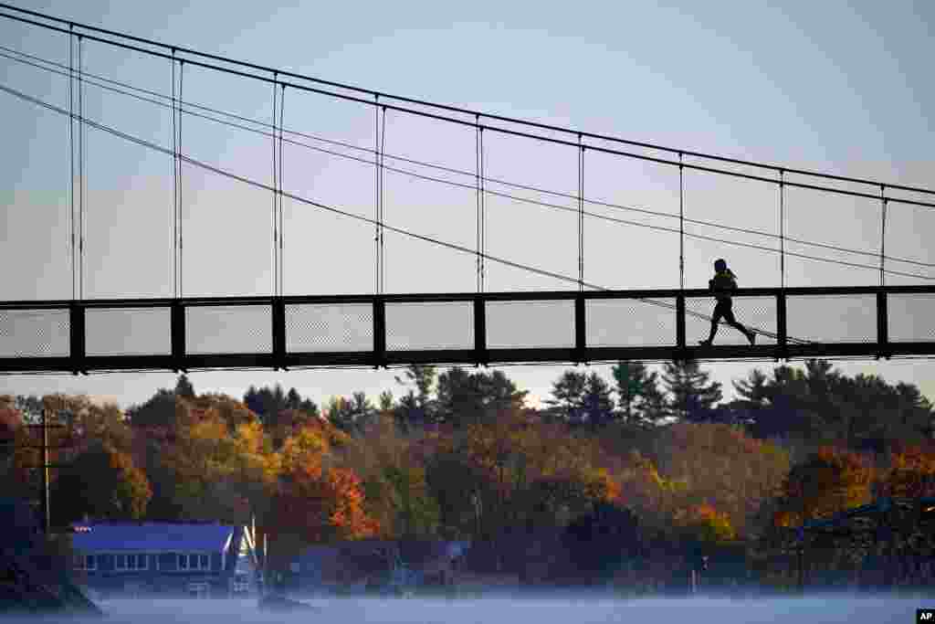 A jogger crosses the Swinging Bridge over the Androscoggin River on a frosty autumn morning, in Brunswick, Maine.