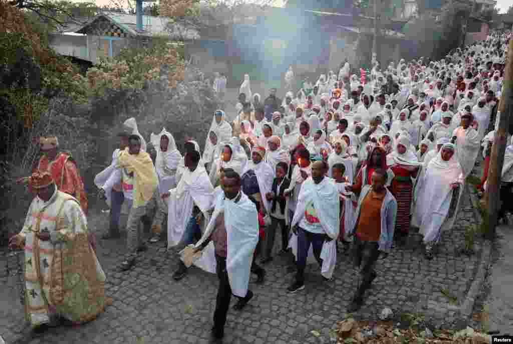 Ethiopian Orthodox Christian faithful hold candles as they receive a blessing from a priest holding burning incense, which according to their beliefs, will keep the coronavirus away, in Addis Ababa, Ethiopia.