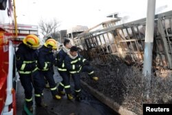 Firefighters work next to burnt vehicles following a blast near a chemical plant in Zhangjiakou, Hebei province, China, Nov. 28, 2018.