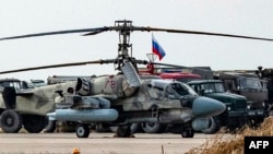 ARCHIVO - Un helicóptero de ataque militar Kamov Ka-52 Alligator de la Fuerza Aérea rusa es fotografiado junto a otros camiones y vehículos en la base aérea rusa del aeropuerto de Qamishli, en el noreste de Siria, el 12 de diciembre de 2024. AFP