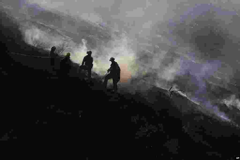 Firefighters stand on a scorched hillside as a wildfire burns in the Hollywood Hills section of Los Angeles, California, July 19, 2016.