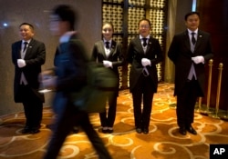 In this Sept. 25, 2015 photo, Chinese butler school graduates stand at attention at a conference in Beijing. A butler is a new must-have for some of China’s super-rich.
