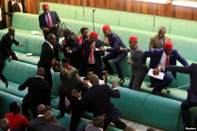 FILE - Ugandan opposition lawmakers fight with plainclothes security personnel in the parliament while protesting a plan to remove the 75-year age limit for the presidency, in Kampala, Sept. 27, 2017.