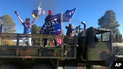 Supporters of President Donald Trump ride in the back of a truck outside the Statehouse in Santa Fe, N.M., on Jan. 6, 2021, to protest President-elect Joe Biden's electoral victory.