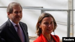 FILE - EU High Representative for Foreign Affairs Federica Mogherini and European Commissioner for European Neighborhood Policy and Enlargement Negotiations Johannes Hahn arrive before signing of an accord to settle a long dispute over the former Yugoslav republic Macedonia's name in the village of Psarades, in Prespes, Greece, June 17, 2018. 